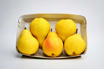 Seasonal fresh pears on the paper box, top view, fresh seasonla fruit biological and pesticides free. Box of yellow pears on a white background top view.