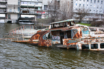 Old rusty sunken ship in the water on the territory of the river port. Old sunken boat on the river.