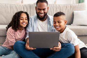 Happy african american family using laptop in living room