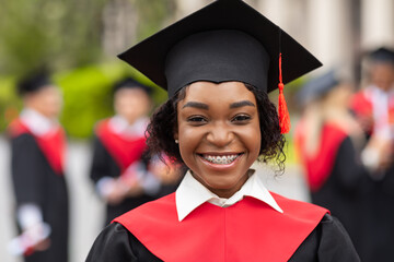 Closeup portrait of happy black lady student wearing graduating costume