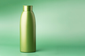 Green cosmetic bottle isolated on mint green background with copyspace. Container for cosmetics product. Skincare and beauty concept.