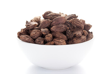 close-up of Organic Black cardamom (Amomum subulatum)  on a ceramic white bowl. Pile of Indian Aromatic Spice. 