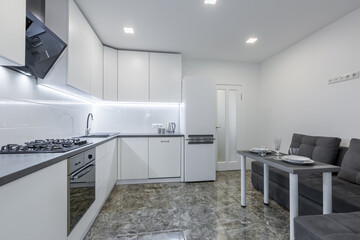 Interior photo, modern kitchen, in light white tones, with black marble tiles on the floor, placed in a small apartment