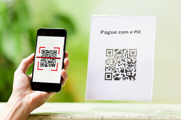 QR Code facilitating payments and electronic money transfers. Closeup of a hand holding a...