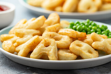 Letters potato fries snack with green peas and ketchup on plate. party food