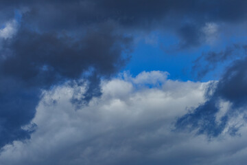 Naklejka na ściany i meble Dark storm clouds on a bright blue sky. Sky patterns background 2021.