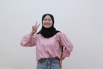 Portrait of beautiful young asian woman has an cute face up two finger on white background. Beautiful asian woman with casual dress. Beautiful muslim women. 