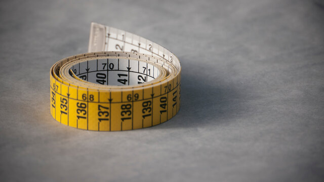 Cinta métrica amarilla y blanca sobre papel blanco arrugado