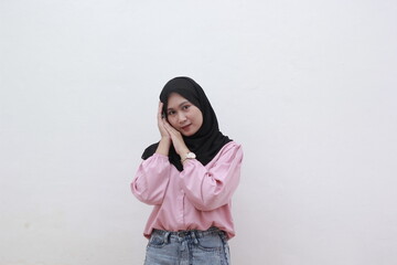 Portrait of confident young Asian woman has an cute face and put his hands as if he were sleeping on white background. Beautiful asian woman with casual dress. Beautiful muslim women. 