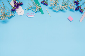 Manicure tools on a blue background are decorated with white gypsophila flowers. The concept of beauty. Copy space. top view