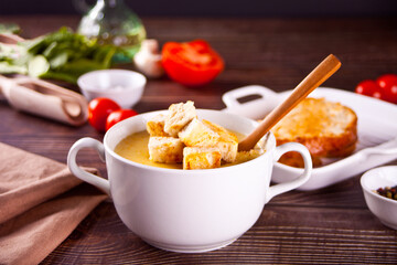 Cheese or onion cream soup with toasts bread in a white bowl