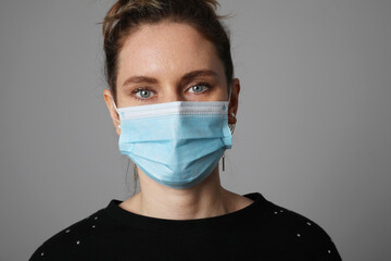 Young woman wearing medical face mask isolated on yellow background. 