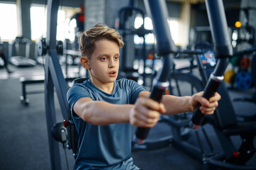 Fototapeta na wymiar Boy on exercise machine, fit training in gym