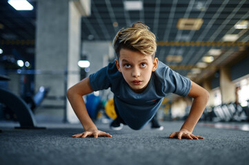 Boy doing push up exercise in gym, front view