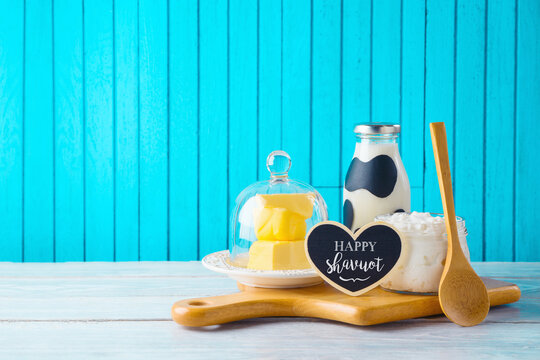 Jewish holiday Shavuot background with milk, cottage cheese and butter on wooden table