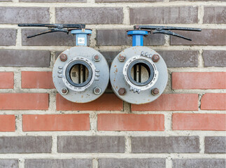 Double fire hydrant on the red brick wall.
