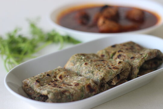Indian flat bread made of whole wheat flour with grounded flax seed and fresh coriander leaves served with red gravy fish curry