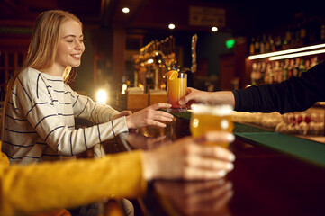 Female friends drinks alcohol at counter in bar