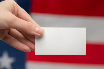 Obraz premium Empty card in woman hand. Copy space. American flag background.
