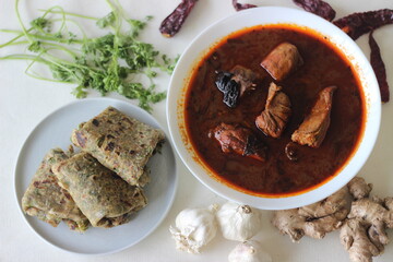 Indian flat bread made of whole wheat flour with grounded flax seed and fresh coriander leaves served with red gravy fish curry