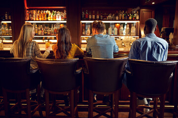 Four friends at the counter in bar, back view
