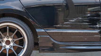 Damaged scratch on black car surface after accident