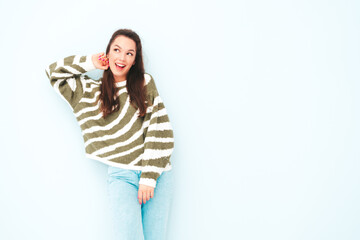 Young beautiful smiling female in trendy summer hipster clothes. Sexy carefree woman posing near light blue wall in studio. Positive model having fun indoors. Cheerful and happy