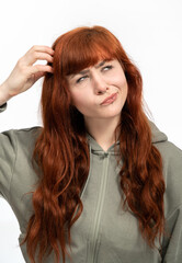 Portrait of girl with red hair infront of white background scratching head while thinking