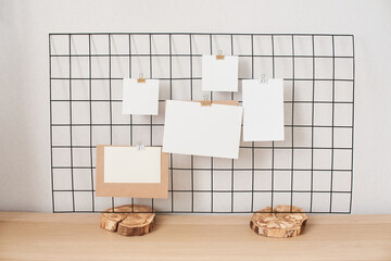 Cards and posters mock ups on black grid board on wooden stand. Blank paper in different sizes...