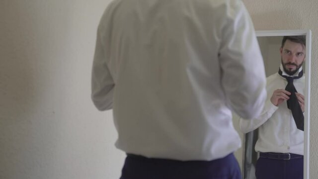 Young Businessman Looking At Himself In Mirror Indoors, Adjusting Necktie And Getting Ready To Go To Work
