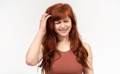 Portrait of girl with red hair infront of white background making faces and scratching head