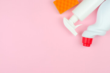 White bottles with detergents and cleaning products and a sponge on a rose background with place for text. Cleaning products on a pink background.