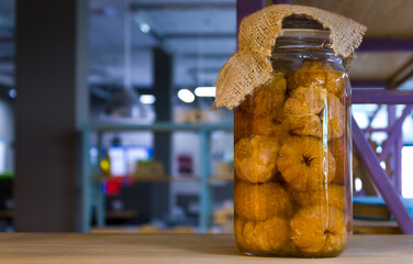 glass mason jar with canned peeled oranges on a wooden desk against the blurred restaurant interior...