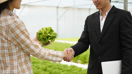 Agribusiness concept Farmer and businessman shaking hand with hydroponic farm background and food supply chain