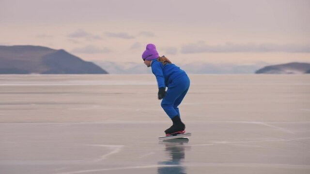 The girl train on ice speed skating. The child skates in the winter in blue sportswear suit, sport glasses. Children speed skating sport.