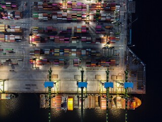 Aerial view of Container ship loading and unloading in deep sea port, logistic import and export freight transportation by container ship in open sea at night. Jakarta, Indonesia, April 12, 2021