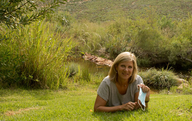Mature blonde woman throws away Covid mask in nature