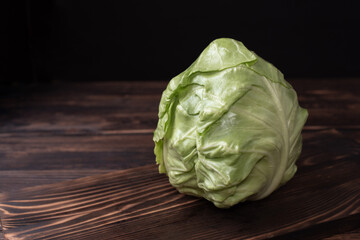 Head of early cabbage on a cutting board on a dark wooden background rustic style.