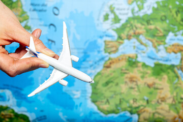 Passenger plane in a female hand on the background of the globe. Flight concept on a light background.