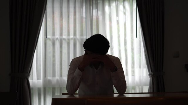 Silhouette of a sad man sitting in the dark, Domestic violence, family problems, Stress, violence, The concept of depression and suicide
