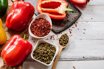 Dry seeds of pepper and raw fresh pepper on wooden background