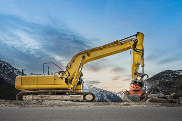Side view of a heavy yellow grab excavator with grapple for natural stone masonry finishing