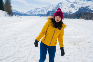Fototapeta na wymiar Winter holidays in the snow - lifestyle portrait of young happy and beautiful Asian Japanese girl enjoying playful at frozen lake in snowy mountains at Swiss Alps