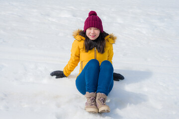 Fototapeta na wymiar Winter holidays in the snow - lifestyle portrait of young happy and beautiful Asian Chinese girl enjoying playful at frozen lake in snowy mountains at Swiss Alps
