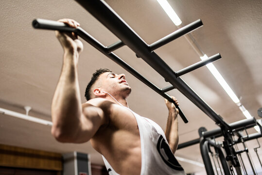 man performs barbell pull-ups in a gym