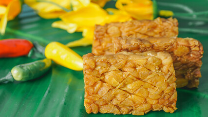 Selective Focus - Fried tempeh for snack on banana leaf. Made by a natural culturing and controlled fermentation process that binds soybeands into a cake form.