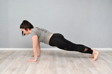 Young beautiful woman doing online sport indoors. Stay at home concept. Woman makes online fitness with laptop.