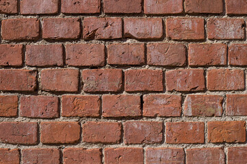The wall is made of old red brick.