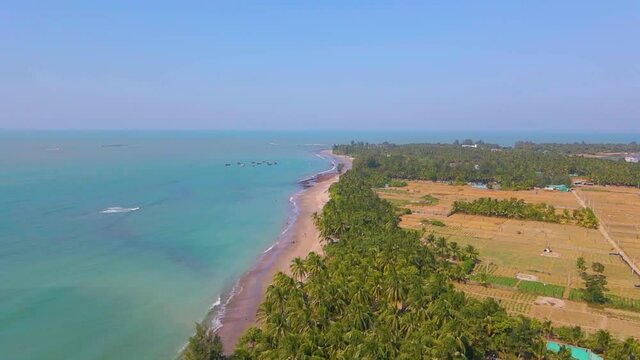 Aerial view of a beautiful green tropical island surrounded by vast ocean. Waves breaking on the beach. Tilt up drone shot. Saint martin, Bangladesh