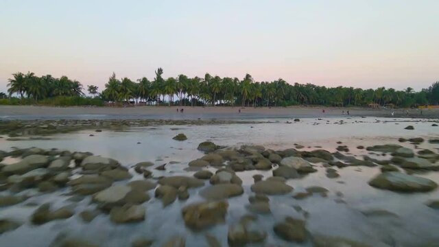 Exotic coral beach with a few tourists in saint martin island, Bangladesh. shallow calm water - Aerial sunset clip.